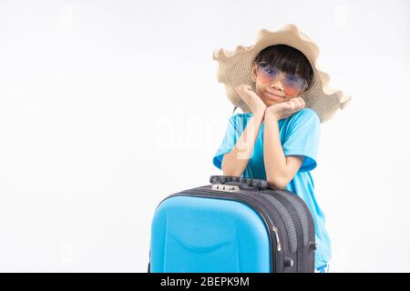 Portrait des jungen asiatischen Kind mit Reisetasche, Thai-Mädchen trägt im Sommer-Stil in blauem Hemd Vorbereitung auf Meer gegen weiße Wand im Studio Stockfoto