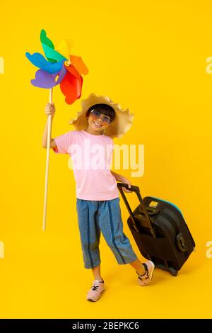 Porträt von jungen asiatischen hübschen Mädchen mit bunten Turbine und ziehen blauen Reisetasche, Thai Kind im Sommer-Stil auf gelbem Hintergrund Stockfoto