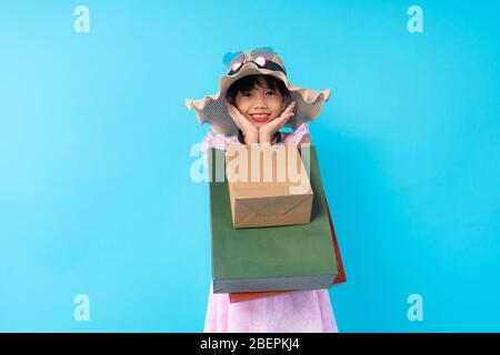 Glücklich junge asiatische Mädchen Kind stilvolle Holding Einkaufstasche auf blauem Hintergrund im Studio, Lifestyle von bezahlten für Kinder Mode-Stil-Konzept Stockfoto