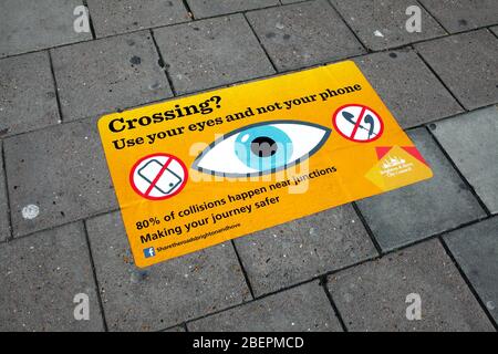 Warnschild, auf einem Bürgersteig, positioniert, um von Menschen, die auf ihre Handys, anstatt zu sehen, wo sie gehen zu sehen. Stockfoto