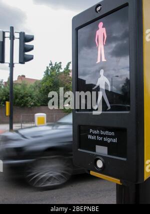 Roter Mann auf Fußgängerübergangsschild, wenn ein Auto durch die Ampel fährt. Stockfoto