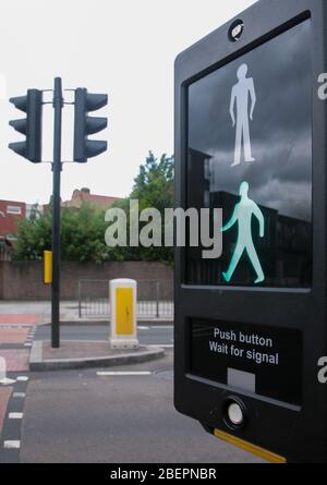 Grüner Mann auf Fußgängerüberweg Schild an der Ampel am Straßenrand. Stockfoto
