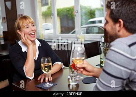 Lachende Frau im Restaurant, die mit einem Mann spricht Stockfoto