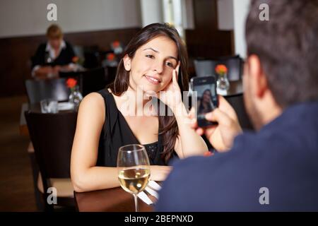 Mann mit Handy fotografiert Frau im Restaurant Stockfoto