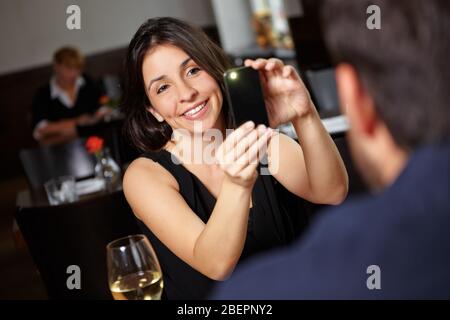 Frau fotografiert ihren Partner mit Handy im Restaurant Stockfoto