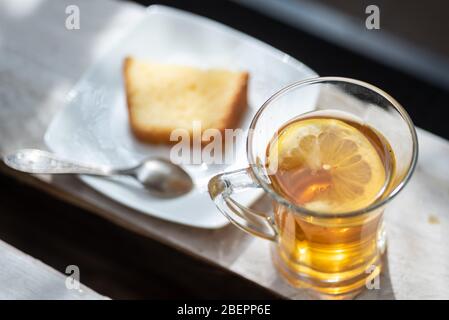 Frisch zubereitetes Glas schwarzen oder grünen Tee mit Zitrone zum Frühstück serviert draußen an sonnigen Tag Stockfoto