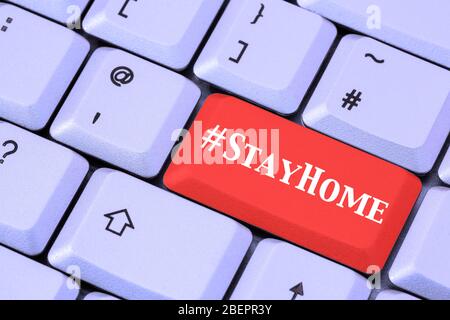 Eine Tastatur mit #StayHome auf einer roten ENTER-Taste. Covid-19 Coronavirus-Pandemie bleibt zu Hause Lockdown-Konzept im April 2020. England, Großbritannien Stockfoto
