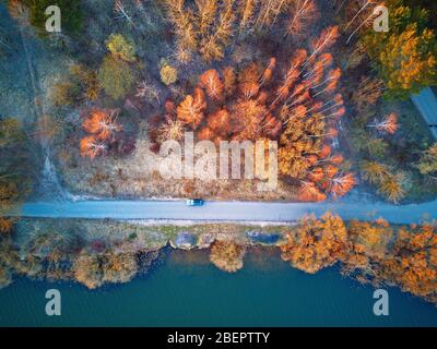 Am See mit bunten Bäumen im Frühling Sonnenlicht. Auto auf einer Straße, Erholungszone Draufsicht. Der Aprilabend am See neben Minsk, Weißrussland. Wunderschön Stockfoto