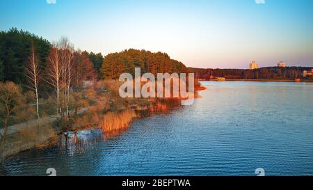 Am See mit bunten Bäumen im Frühling Sonnenlicht. Der Aprilabend am See neben Minsk, Weißrussland. Erholungszone aus der Luft. Wunderschöner Sonnenuntergang Stockfoto