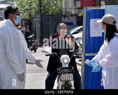 Wuhan, Chinas Provinz Hubei. April 2020. Ein Bewohner scannt den QR-Code für die Gesundheit am Eingang der Chucai Gemeinde im Wuchang Bezirk von Wuhan, der zentralen Provinz Hubei, 15. April 2020. Mit der Wiederaufnahme der Arbeit und der Produktion in Wuhan wurden auch kontinuierliche Anstrengungen unternommen, um epidemische Präventionsmaßnahmen wie die Körpertemperatur und die Überprüfung des QR-Codes in den Gemeinden durchzuführen. Kredit: Li He/Xinhua/Alamy Live News Stockfoto