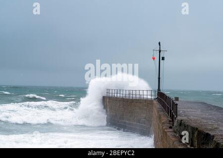 Ein stürmischer Wintertag mit Wellen, die den Hafen in Porthleven, Cornwall England, überfluten Stockfoto