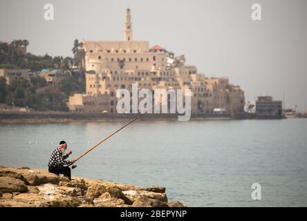 Profilansicht eines lokalen Mannes, der mit Gebäuden im Hintergrund fischt, Tel Aviv, Israel Stockfoto