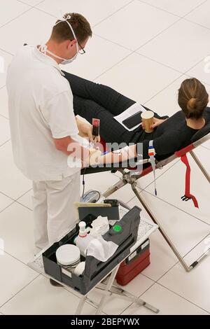 Koblenz, Deutschland. April 2020. Eine Frau spendet Blut im Atrium der Rhein-Mosel-Halle, wo üblicherweise Veranstaltungen stattfinden. Die Blutspender werden vom Deutschen Roten Kreuz (DRK) in größeren Räumen mit mehr Raum zwischen ihnen aufgenommen, da das Infektionsrisiko durch die Corona-Pandemie besteht. Quelle: Thomas Frey/dpa/Alamy Live News Stockfoto