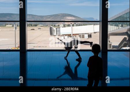 05/26/2019. Flughafen Bodrum / Flughafen Milas Mugla. Türkei. Kleines Mädchen, das Kart-Räder macht, übt aus Langeweile, während es auf ihren Flug wartet. Stockfoto