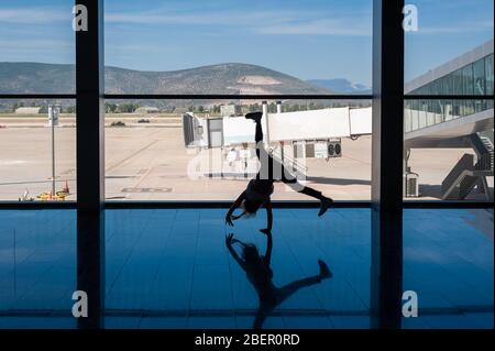 05/26/2019. Flughafen Bodrum / Flughafen Milas Mugla. Türkei. Kleines Mädchen, das Kart-Räder macht, übt aus Langeweile, während es auf ihren Flug wartet. Stockfoto