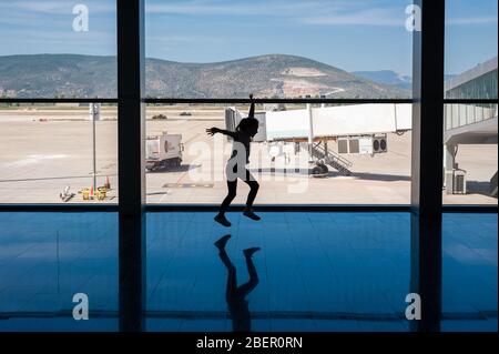 05/26/2019. Flughafen Bodrum / Flughafen Milas Mugla. Türkei. Kleines Mädchen, das Kart-Räder macht, übt aus Langeweile, während es auf ihren Flug wartet. Stockfoto