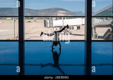 05/26/2019. Flughafen Bodrum / Flughafen Milas Mugla. Türkei. Kleines Mädchen, das Kart-Räder macht, übt aus Langeweile, während es auf ihren Flug wartet. Stockfoto