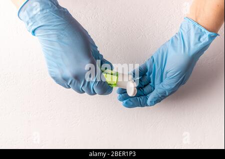Hände in Gummi-OP-Handschuhe tragen antiseptische Hand Desinfektionsmittel auf hellen Hintergrund. Draufsicht. Kopierbereich Stockfoto