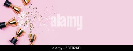 Goldene Gewinner Tassen mit funkelt auf einem rosa Hintergrund mit Kopierraum. Festliches Konzept. Flaches Lay-Design. Stockfoto