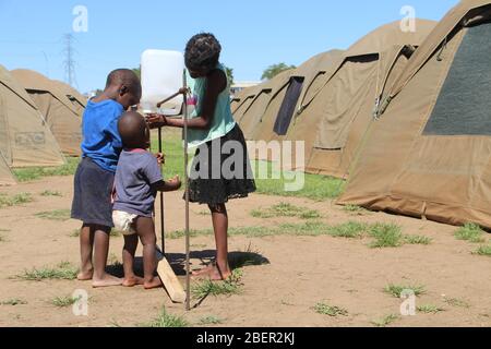 (200415) -- WINDHOEK, 15. April 2020 (Xinhua) -- Obdachlose Kinder waschen sich die Hände mit Tippy-Tap Handwaschtechniken vor temporären Zelten in Windhoek, Namibia, 14. April 2020. Der Tippy-Tap ist eine gängige Praxis in informellen Siedlungen, in denen Menschen keinen Zugang zu fließendem Wasser haben. Die Technik wird dringend empfohlen, um die namibische Regierung bei ihren Lockdown-Bemühungen im Kampf gegen die COVID-19-Pandemie zu unterstützen. (Xinhua/Jacobina Mouton)