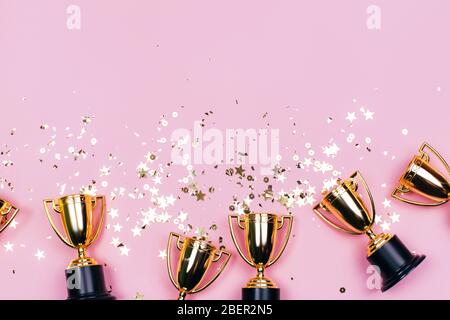 Goldene Gewinner Tassen mit funkelt auf einem rosa Hintergrund mit Kopierraum. Festliches Konzept. Flaches Lay-Design. Stockfoto