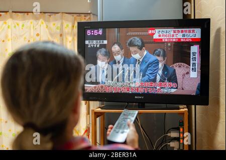 Fuji City, Shizuoka, Japan - 7. April 2020: Eine Frau sieht Japan Premierminister Shinzo Abe im Fernsehen über die Erklärung des Ausnahmezustands über das Coronavirus. Stockfoto