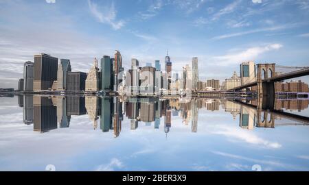 New york Skyline Reflexion auf dem Hudson River an der Brooklyn Bridge bei hellem Tageslicht Stockfoto