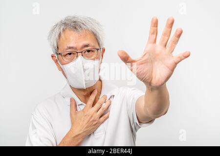 Alter Asiat Mann trägt N95 Maske hält seine linke Hand mit Palme aus Stretch bitten um Hilfe mit seiner rechten Hand berühren seine Brust, Gesundheit oder Sanitäter Stockfoto