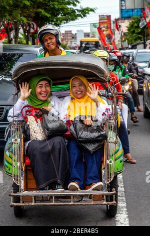 Zwei Lächelnde Indonesische Frauen, Die Mit Dem Motorrad-Taxi In Yogyakarta, Indonesien Reisen. Stockfoto