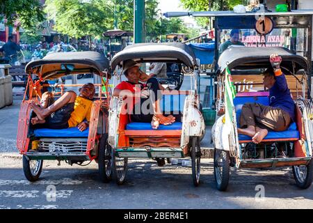 Becak (Cycle Rickshaw) und Motorrad Taxi Drivers Ruhen, Yogyakarta, Java, Indonesien. Stockfoto