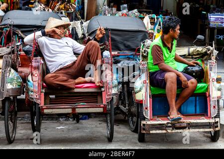 Becak (Cycle Rickshaw) und Motorrad Taxi Fahrer warten auf Business, Malioboro Street, Yogyakarta, Java, Indonesien. Stockfoto