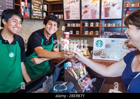 Lima Peru, Starbucks Coffee, innen Barista Baristas Cafe, Theke, serviert grünen Schürze Kassierer, lattee Cup, lächelnde hispanische Jungen männlichen Teenagern Frau Stockfoto