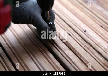 DIY Bau einer Veranda / Balkon Boden mit braunen Holzbohlen in Espoo, Finnland, Februar, 2020. Person, die Bohrmaschine verwendet, um den Boden zu bauen. Stockfoto