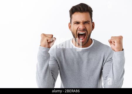 Champion, Sport und Gebotskonzept. Gut aussehende energiegeladen und aufgeregt stattlichen Kerl triumphierend, schütteln geballte Fäuste als Sieg feiern Stockfoto