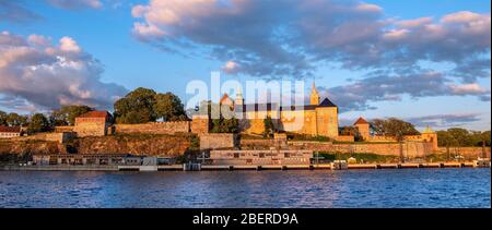 Oslo, Ostlandet / Norwegen - 2019/09/02: Sonnenuntergang Blick auf mittelalterliche Akershus Festung - Akershus Festning - historische königliche Residenz am Oslofjorden Meer sho Stockfoto