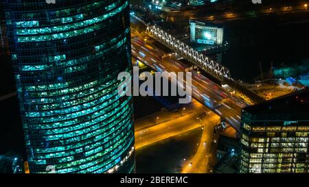 Wolkenkratzer, schnell fahrender Autoverkehr und warmes Straßenlicht in der Nacht Stockfoto