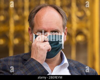 Dresden, Deutschland. April 2020. Dirk Hilbert (FDP), Oberbürgermeister der Stadt Dresden, trägt bei der Übergabe der selbst genähten Stoffmasken durch Näherinnen des Vietnamesischen Frauenclubs Dresden eine Gesichtsmaske vor dem Rathaus. Mitglieder des Vietnamesischen Frauenclubs Dresden haben in den vergangenen Wochen mehrere tausend Mundschutz genäht. Diese wurden dem Krankenhaus Friedrichstadt, dem Universitätsklinikum Dresden, der Volkssolidarität Dresden, Seniorenzentren und Allgemeinmedizinern gespendet. Quelle: Robert Michael/dpa-Zentralbild/dpa/Alamy Live News Stockfoto