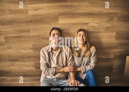 Schöne glücklich schönes Paar auf dem Boden sitzen und hinter der Wand nach dem Umzug in eine neue Wohnung. Stockfoto