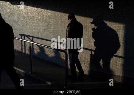 Istanbul, Türkei - 12. März 2011 : Junge Männer gehen und rauchen Zigaretten und Schatten von Menschen an der Wand in Istanbul. Stockfoto