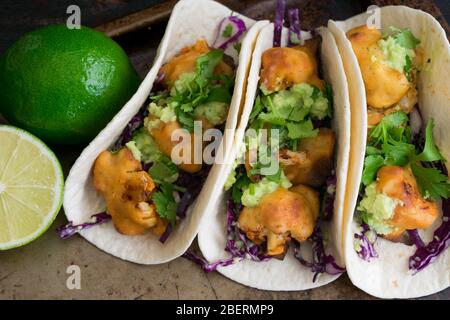 Buffalo Cauliflower Tacos mit Avocado Crema: Vegetarische Tacos mit würzigem Blumenkohl, Avocado Crema und geschreddertem Kohl Stockfoto