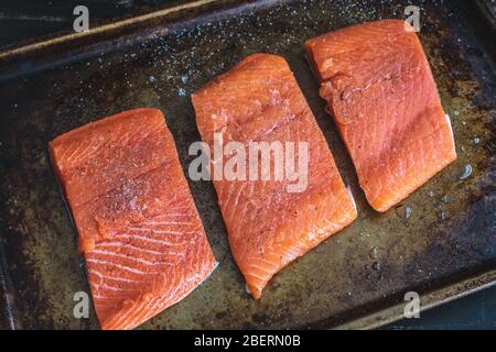 Rohe Lachsfilets auf einer Blechpfanne: Lachsfilets, gewürzt mit Salz und Pfeffer auf einer gebräunten Blechpfanne Stockfoto