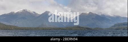 Landschaft mit Manapouri See und Frühlingsschnee auf Hunter Bergkette im Hintergrund, aufgenommen in hellen bewölkten Frühlingslicht in der Nähe von Manapouri, Southland, S Stockfoto