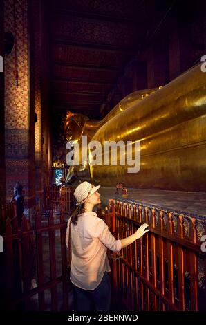 Frau Tourist in der Nähe der Statue des Großen Goldenen Buddha im Wat Pho Tempel in Bangkok, Thailand. Symbol für die buddhistische Kultur. Stockfoto