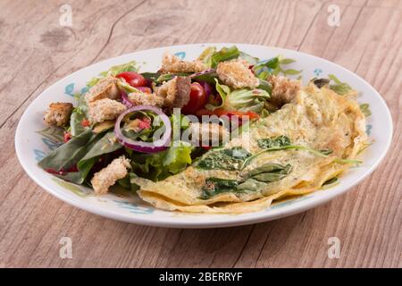 Leaf Salad mit Omelette auf einem Holztisch mischen Stockfoto