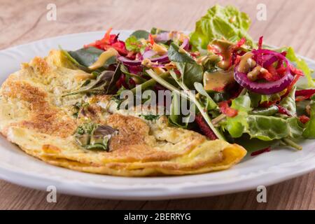 Leaf Salad mit Omelette auf einem Holztisch mischen Stockfoto