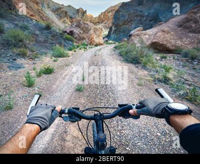 Reiter in Handschuhe holding Lenker Mountainbike in der Wüste Canyon. Extreme Sport Konzept. Stockfoto