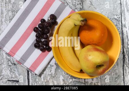 Frisches Obst auf gelbem Teller und Handtuch. Multivitamin-Cocktail. Gesunde Lebensweise Stockfoto