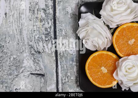 Orangefarbene Scheiben auf einem schwarzen Teller auf einem Holzhintergrund Stockfoto