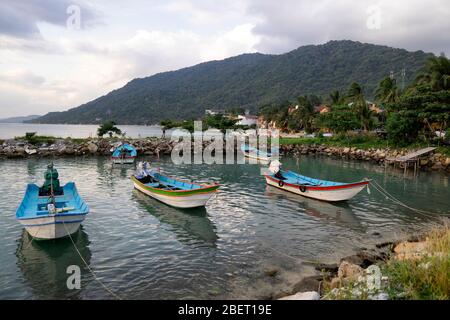 Traditionelle Fischerboote am Pier der Insel Koh Phangan in Thailand bei Sonnenuntergang an einem bewölkten Tag. Stockfoto