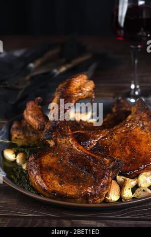 Saftiges, gebratenes Schweinehüsch auf einem Knochen in Öl mit Knoblauch und Kräutern in einer Pfanne. Nahaufnahme. Stockfoto